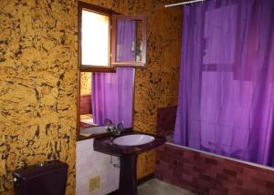 a bathroom with a sink and a purple shower curtain at Tour des hirondelles in Écuras +7 photos