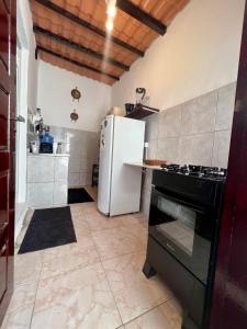 a kitchen with a refrigerator and a stove at Casa estilo chale dúplex com 3 quartos, churrasqueira, balanço, chuveirão e a uma quadra da praia in Mangaratiba