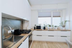 a white kitchen with a sink and a stove at Modern Stay Rîșcani, AC, WiFi, Washer in Chişinău