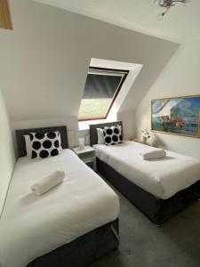 two beds in a room with a window at 3BR House Self Check In Parking By PlushPad in Shenley Lodge +18 photos