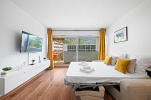 a white bedroom with a large bed and a tv at LE SUN - Central - Piscine - Wifi in Menton