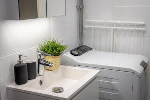 a white bathroom with a sink and a mirror at ULEABO Luxurious And Spacious 55m2 Apartment With Sauna! in Oulu
