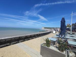 a beach with chairs and umbrellas and the ocean at Loft arty à 800 mètres de la plage avec jacuzzi in Veulettes-sur-Mer