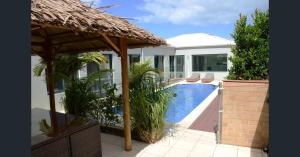 a villa with a swimming pool and a straw umbrella at Coorong GateAway POOL - SPA - SAUNA in Hindmarsh Island