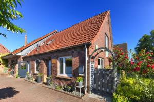 a red brick house with a black fence at Ferienhaus Moorgeist in Stedesdorf
