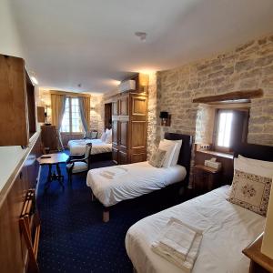 a hotel room with two beds and a chair at Hôtel-Restaurant Le Manoir De Montesquiou in La Malène