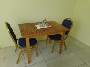 a wooden table with two blue chairs and a wooden table and chairsuggest at Sunflower Inn in Kingstown