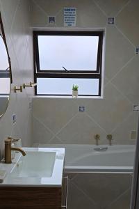 baño blanco con lavabo y ventana en Coastal Cove Langebaan, en Langebaan
