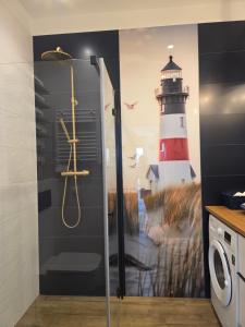 Un baño con ducha con un mural de un faro en la pared. en Sol Marina Apartament Marina Blue, en Wiślinka 3 fotos más