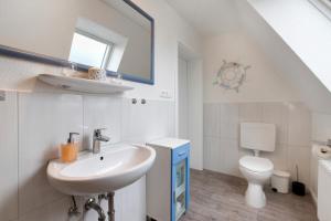 a white bathroom with a sink and a toilet at Ferienwohnung Janina in Norddeich +14 photos