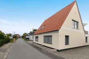 a white house with a red roof on a street at Ferienwohnung Janina in Norddeich