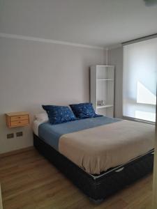 Un dormitorio con una cama grande con almohadas azules. en Departamento Viña del Mar, en Viña del Mar