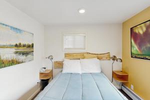 ein Bett in einem Zimmer mit einem Gemälde an der Wand in der Unterkunft Moose Meadow Cottage in Anchorage