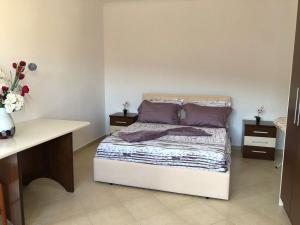 a bedroom with a bed with purple pillows and a desk at House of Leaves in Berat