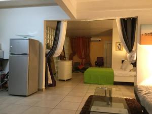 a living room with a refrigerator and a bedroom at Le gîte les haut de la Marina in Basse-Terre