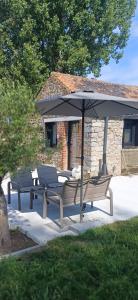 a group of chairs and an umbrella on a patio at Ma Bergerie in Boignée