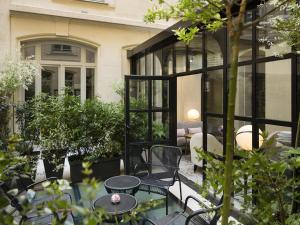 a patio with tables and chairs in front of a house at Le Narcisse Blanc in Paris