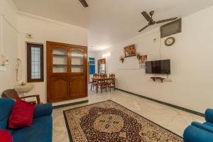 a living room with a blue couch and a tv at Varsha Homestay with Kitchen, Opposite Botanical Garden, 500 meters from New Bus Stand, Railway Station, and Rock Beach, Pondicherry in Puducherry