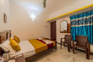 a bedroom with a bed and two chairs in it at Varsha Homestay with Kitchen, Opposite Botanical Garden, 500 meters from New Bus Stand, Railway Station, and Rock Beach, Pondicherry in Puducherry