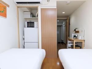 two beds in a small room with a refrigerator at Laze Nakano 2bed Travel Work Broadway in Tokyo