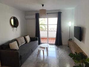 ein Wohnzimmer mit einer Couch und einem Tisch und einem Fenster in der Unterkunft Benalmádena Beach Apartment in Benalmádena