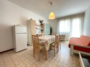 a kitchen and dining room with a table and a refrigerator at Cozy flat with shared pool in Porto Santa Margherita di Caorle