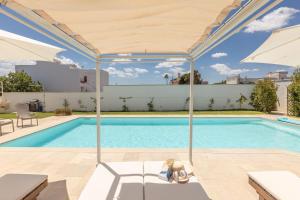 una piscina con sombrilla y una piscina en Villa Estro del Sud, en Gagliano del Capo
