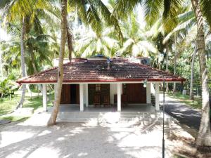 a small house with palm trees in front of it at Gin Oya Villa in Aluttota