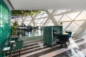 a restaurant with green chairs and tables in a building at Andaz Capital Gate Abu Dhabi, By Hyatt in Abu Dhabi