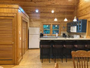 a kitchen with a white refrigerator and black bar stools at Sapphire Cabin at Splendor Mountain in Tiger