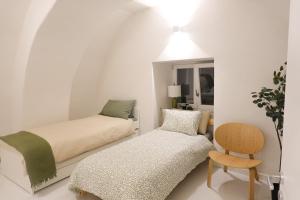 a white bedroom with a bed and a chair at Casa MAR e LUNA in Amalfi