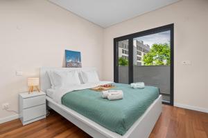 a white bedroom with a large bed and a window at Rooftop Pools & Balcony Haven by HostWise in Faro