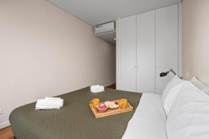a room with a bed with a tray of food on it at Rooftop Pools & Balcony Haven by HostWise in Faro
