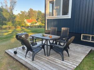 a picnic table and chairs on a deck with a grill at Hus Silverdalen in Silverdalen