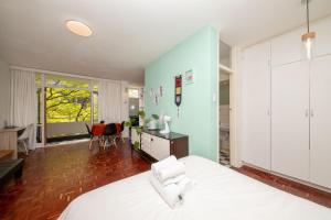a bedroom with a large white bed and a desk at Central Urban Studio with Garden viewSwimming Pool in Cape Town