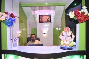 a man sitting at a table in front of a mirror at Kareng Guest House in Kāziranga
