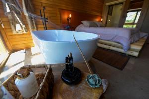 a bathroom with a tub and a bed and a table at Cabana Rústica em Gramado in Gramado