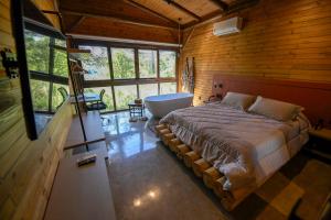a bedroom with a bed and a tub in a room at Cabana Rústica em Gramado in Gramado