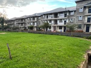 a large grassy field in front of an apartment building at Kef Apartments in Nanyuki