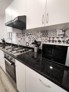 a kitchen with white cabinets and a black counter top at Marca 34 in Monção