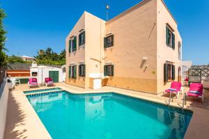 a swimming pool with pink chairs and a house at Villa Matias Maria by Villa Plus in Cala en Blanes