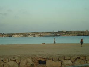 two men walking on the beach near the water at Casa alla Guitgia 2 in Lampedusa