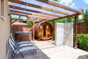 a patio with a wooden pergola and a tub at Molnár Apartman Zamárdi in Zamárdi