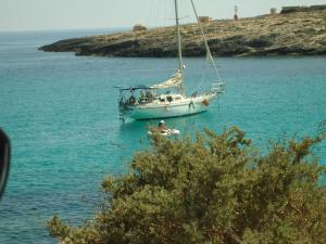 a sail boat in the water with a person in a raft at Casa alla Guitgia 2 in Lampedusa