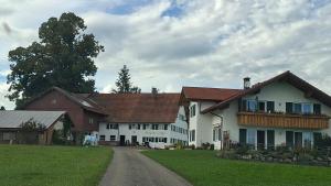a large white house with red roofs on a field at Hengeler's hof in Altusried