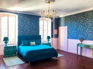 a bedroom with blue walls and a bed and a chandelier at Chateau de la Coutere in Saint-Laurent