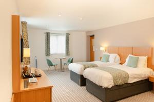 a hotel room with two beds and a table and chairs at Deangate Motel in Lydney