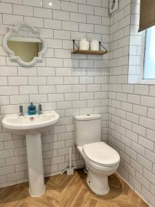 a white bathroom with a toilet and a sink at Pendene in Hinton