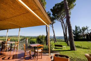 a patio with a table and chairs and trees at Villa Il Fedino in San Casciano in Val di Pesa