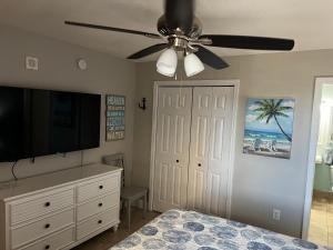 a bedroom with a ceiling fan and a television at Panama City Beach, Beach Front Condo 207 in Panama City Beach